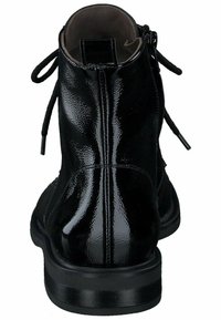 Botas negras hasta el tobillo con un brillante acabado de cuero sintético, puntera redondeada y cierre con cordones con lazos decorativos. Suela plana con ligeros relieves.