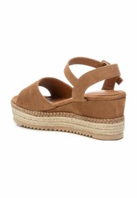 Sandal de cuña de ante marrón con correas entrecruzadas, punta abierta y suela de yute trenzado. Presenta una plataforma texturizada y un cierre de hebilla trasero.