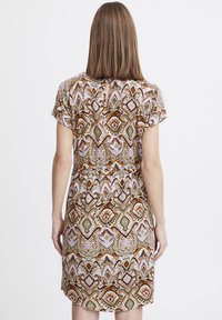Vestido de manga corta con un patrón geométrico colorido en marrones, verdes y rosas, con un corte en forma de llavero en la parte posterior y un ajuste relajado.
