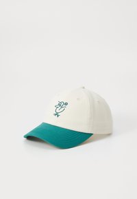Casquette de baseball en coton avec une couronne crème et une visière teal. Présente un design d'oiseau brodé sur le devant. Six œillets de ventilation sur la couronne.