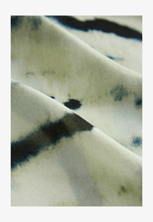 De textiel heeft een licht crèmekleurige achtergrond met donkerblauwe en zwarte abstracte patronen, en vertoont een zachte, gladde textuur en een subtiele glans.