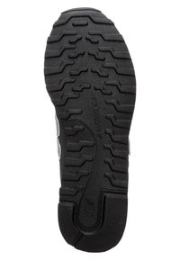 Svart gummisul med en texturerad mönsterdesign med varierande djup för grepp och hållbarhet. "New Balance"-logotyp synlig.