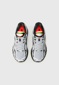 Pair of white and black running shoes with neon green and orange accents shown from above on a light background.