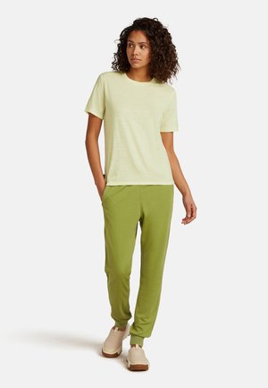Light yellow short-sleeve T-shirt paired with green jogger pants. The outfit features a relaxed fit and soft, textured fabric.