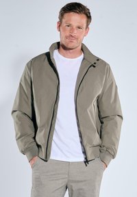 Men's bomber jacket in light gray fabric, featuring a zip closure, high collar with snap buttons, and ribbed cuffs. Smooth texture and minimal design.