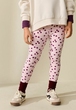 Legginsy w jasnoróżowym kolorze z ciemnofioletowymi groszkami, dopasowany krój. Połączone z luźną kremową bluzą i bordowymi prążkowanymi mankietami. Buty casualowe.