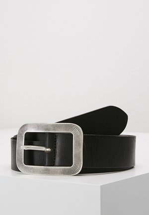 Ceinture en cuir noir avec une grande boucle rectangulaire argentée texturée, présentée enroulée sur une surface blanche sur fond gris clair.