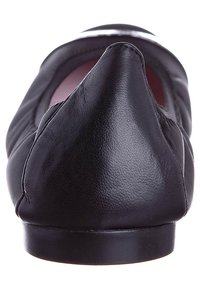 Černé kožené slip-on boty s špičatou špičkou, hladkou texturou a minimalistickým designem. Mají plochou podrážku a žádný viditelný kovový prvek.