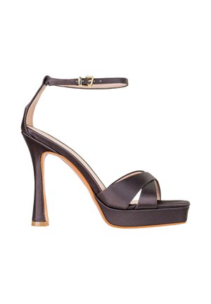 Sandalo nero in raso con tacco alto e plateau, sottile cinturino alla caviglia, fibbia dorata e cinturini frontali incrociati su sfondo bianco.