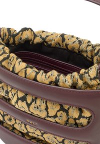 Väska med yttre i mörkröd läder och insidan klädd i gult och svart mönstrat tyg; har en samlad topp och detaljer i guld.