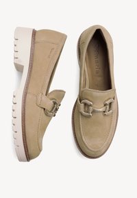 Beige suède loafers met een decoratieve metalen band, rubberen buitenzool en een blokhak, met stikdetails en een soepele textuur.