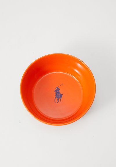 Oranžs plastmasas trauks ar gludu virsmu. Centrā bāzē ir purpura polo spēlētāja logotips. Apaļveida forma ar noapaļotiem malām.