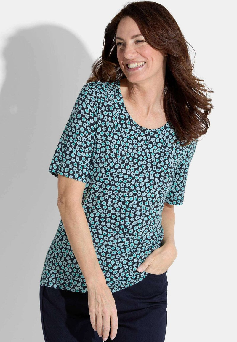 T-shirt à manches courtes avec un fond noir et de petits motifs floraux bleu clair. Tissu lisse et encolure ronde.