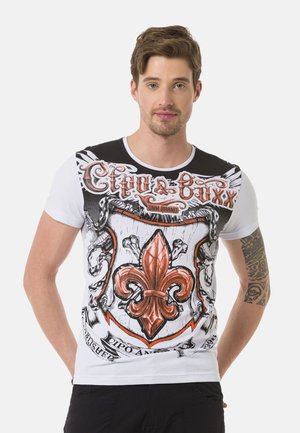 Korte mouwen, wit T-shirt met een gedurfde zwart-rode graphic van een fleur-de-lis wapen, gedetailleerde schedels en een draaiend tekstontwerp.