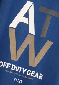 Blauwe katoenen T-shirt met grote witte, bruine en grijze letters: "ATW OFF DUTY GEAR 223 AALBORG TACTICAL WING HALO."