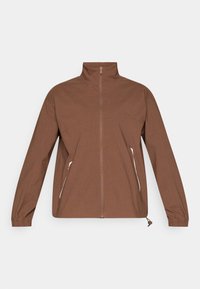 Καφέ ζακέτα με φερμουάρ, ψηλό γιακά, ελαστικά μανίκια και πλαϊνές τσέπες με λευκά φερμουάρ. Λείο, ελαφρύ ύφασμα με ματ φινίρισμα.