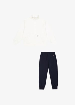 Giacca bianca con zip e pantaloni jogger blu scuro. La giacca presenta tasche laterali e un logo discreto. I jogger hanno una cintura elastica e bordi a costine.