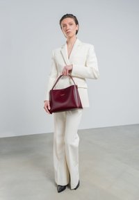 Burgunderfarbene Lederhandtasche mit strukturiertem Design und zwei oberen Griffen, ausgestattet mit dezentem Branding und einer eleganten, hochglänzenden Oberfläche.
