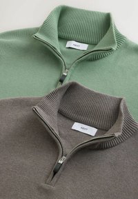 Dwie polarowe bluzy z zamkiem błyskawicznym: jedna jasnoszara, a druga taupe. Obie mają prążkowane kołnierze i teksturowany materiał. Metki prezentują napis "NEXT."