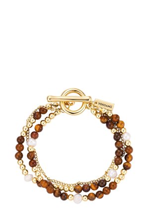 Gouden armband met schakelgesp en drie strengen kralen in bruin, goud en wit, voorzien van een klein rechthoekig label gegraveerd met "YOKOAMii".