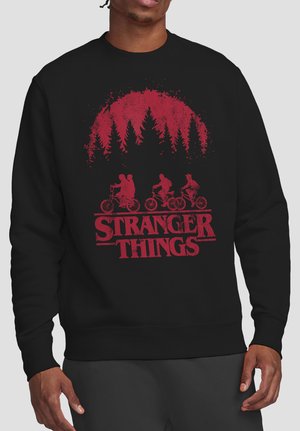 Black sweatshirt with red graphic of three kids riding bicycles under a forest silhouette and bold "Stranger Things" text.