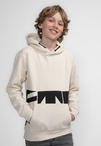 Hoodie color crema con testo grafico nero sulla parte inferiore, dotato di tasca frontale, cappuccio con cordino e polsini a coste.