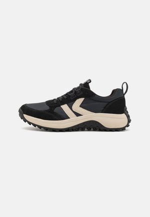 Sportlicher Schuh mit einem Obermaterial in Schwarz und Dunkelgrau, Suede-Akzenten, beiger Zwischensohle und einer strukturierten schwarzen Gummisohle.