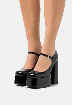 Scarpe platform Mary Jane in vernice nera, con punta arrotondata, cinturino alla caviglia e tacco alto chunky. Finitura lucida e design elegante.