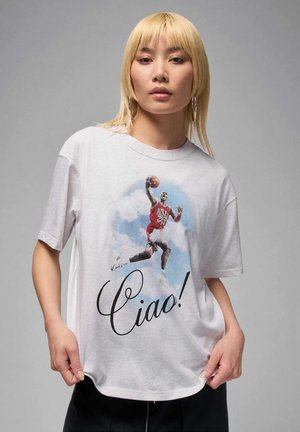 Balts kokvilnas T-krekls ar grafiku, kurā attēlots basketbola spēlētājs, un apakšā melnā krāsā drukāti biezi, rakstīti vārdi "Ciao!".
