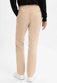 Beige broek met een rechte pijp design, gemaakt van gladde stof. Heeft een achterzak en wordt gedragen met witte plateau sneakers.