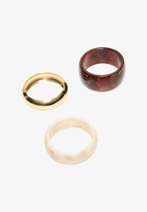 Trei inele late, netede, în aur, maro marmorat și crem marmorat, aranjate pe un fundal alb.