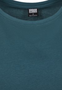 Kortärmad turkos t-shirt tillverkad av en bomullsblandning, med en klassisk rund halsringning och en etikett med texten "URBAN CLASSICS" inuti.