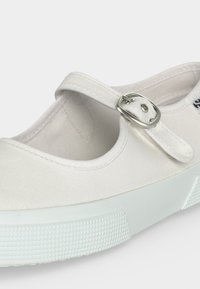 Λευκό παπούτσι Mary Jane με στρογγυλεμένη μύτη, ασημένια αγκράφα και υφασμένο λευκό καουτσούκ πάτο.