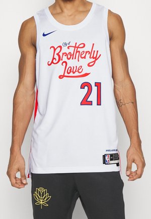 Maglia da basket bianca con dettagli rossi, testo blu con la scritta "Città dell'Amore Fraterno", numero 21 e logo NBA. Realizzata in materiale traspirante.