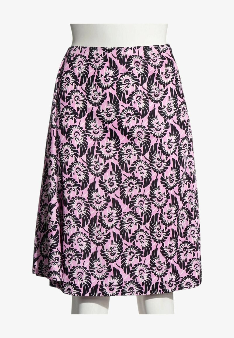 Jupe rose mi-longue avec motif floral noir et blanc répétitif exposée sur un mannequin blanc.