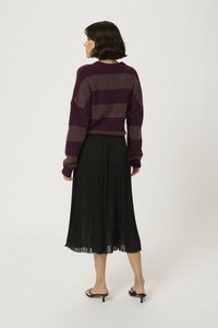 Kudunud, burgundia triibuline lühike sviiter, millele on sobitatud volditud must midi seelik; sile tekstuur, avatud seljaga ja mustade kontsadega sandaalid.