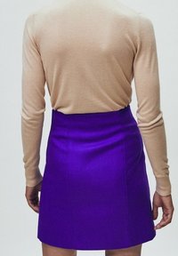 Beżowy sweter z mieszanki wełny, dopasowany; fioletowa spódnica mini w kształcie litery A z teksturowanej powierzchni i wysokim stanem.
