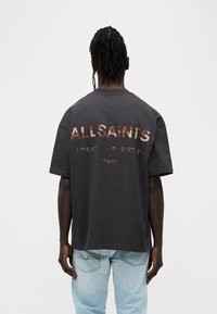 Μαύρο βαμβακερό T-shirt μεγάλης διάστασης με ξεθωριασμένο γράφημα και κείμενο "ALLSAINTS" σε διάφορες γλώσσες στην πλάτη. Καθημερινό σχέδιο με στρογγυλή λαιμόκοψη.