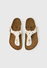 Bele sandale z rožnatimi okraski, z zaponko in teksturirano rjavo notranjo podplato. Ravna podplata, primerna za priložnostno nošenje.