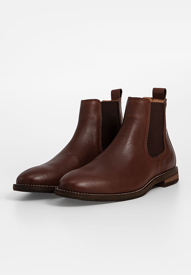 Braune Leder-Chelsea-Boots mit elastischen Seitenpaneelen, runden Zehen und einem niedrigen, gestapelten Absatz. Glatte Textur mit feinen Nähten.