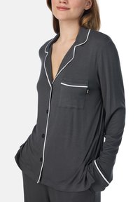 Pigiama con top a maniche lunghe grigio in un tessuto liscio, con piping bianco, una tasca sul lato sinistro del petto e un design con bottoni sul davanti.