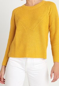 Gelbes gestricktes Sweatshirt mit rundem Ausschnitt, strukturiertem Stoff und einem V-Muster-Detail auf der Vorderseite. Lange Ärmel und eine lockere Passform.