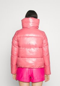 Chaqueta acolchada de material brillante en color rosa con cuello alto y diseño acolchado. Presenta un acolchado voluminoso y una silueta ajustada.