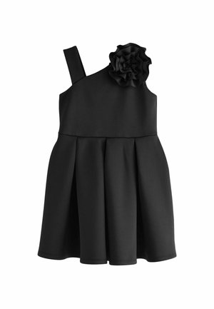 Robe noire avec une bretelle unique, ornée d'un accent floral texturé. Jupe plissée et tissu lisse mat. Design simple et structuré.