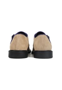 Brązowe zamszowe buty z fioletowym skórzanym kołnierzem, posiadające czarną podeszwę i dekoracyjne klamry po obu stronach.