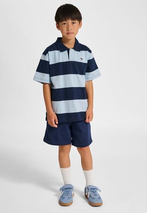 Blå og marineblå stribet poloshirt med krave, kombineret med marineblå shorts og lyseblå sneakers. Har korte ærmer og crew-længde sokker.