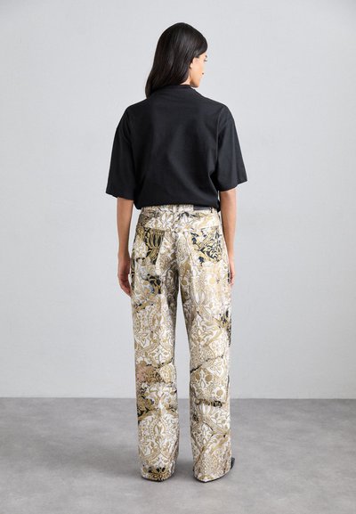 Tricou scurt negru cu mânecă scurtă asociat cu pantaloni largi, cu un model ce conține designuri aurii, albe și negre. Textură moale, croi lejer și picioare largi.