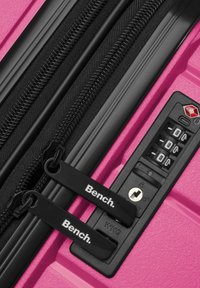 Valigia rosa con cerniere nere e lucchetto a combinazione; presenta il marchio sui tirazip e una superficie texture per una migliore presa.