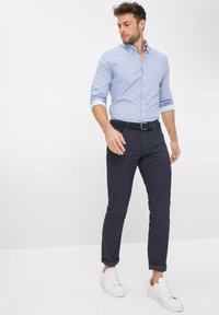 Hellblau kariertes Langarmhemd, dunkelblaue schmale Hose und weiße Turnschuhe. Der Stoff wirkt glatt, die Ärmel sind hochgekrempelt, und es wird ein schwarzer Gürtel getragen.