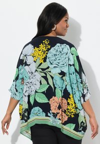 Kimono nero fluido con fiori grandi in teal, giallo e corallo, con un motivo di foglie verdi e un dettaglio a strisce sull'orlo inferiore.